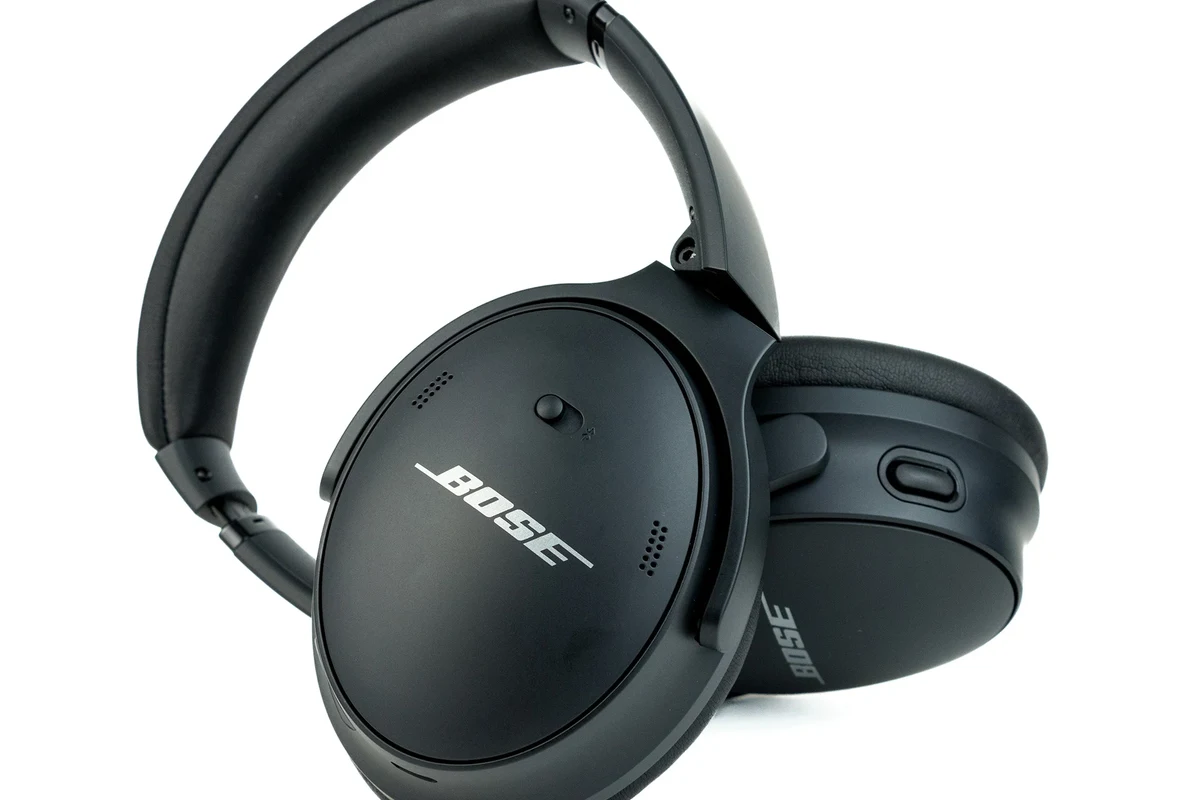 Bose wireless headphones on a desk with a phone showing app-based device location