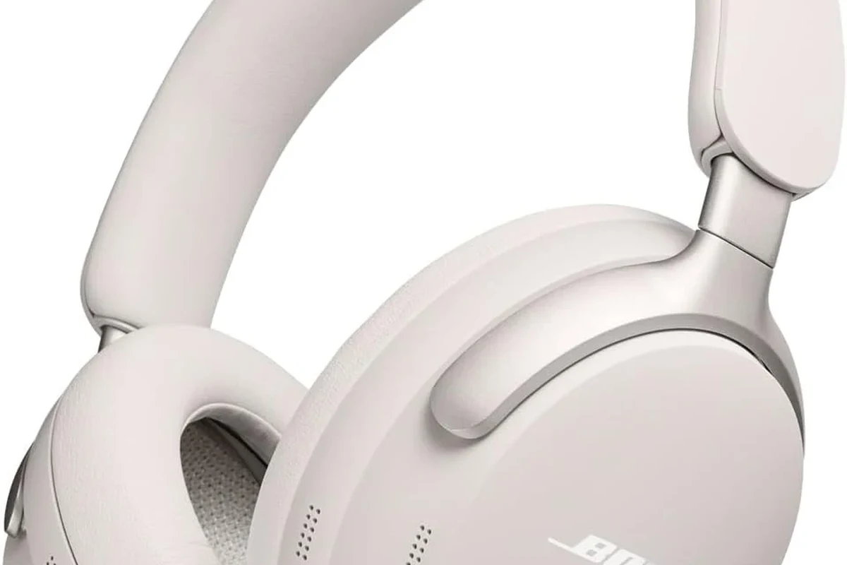 Bose wireless headphones on a desk with a phone showing Bluetooth connection settings