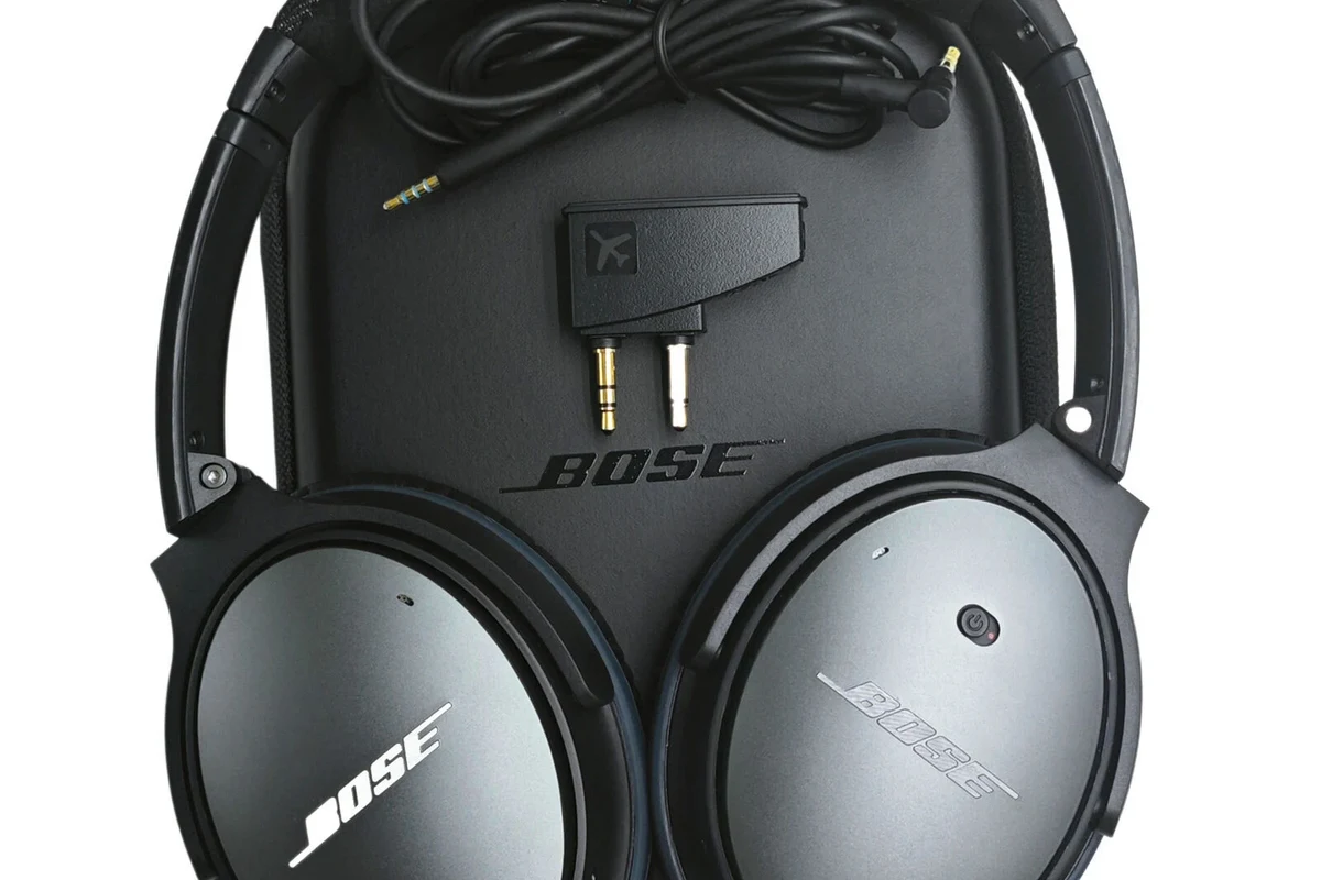 Bose over-ear headphones with detachable cable on a desk beside travel gear
