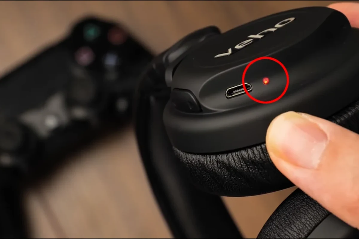 Person connecting wired headphones to a PS4 controller for gaming audio