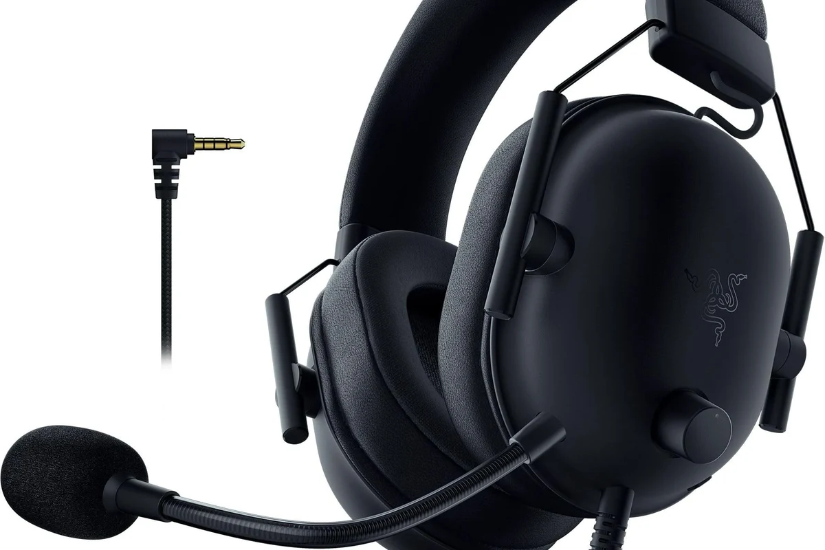 JBL headphones connected to a PS5 controller beside a gaming console setup
