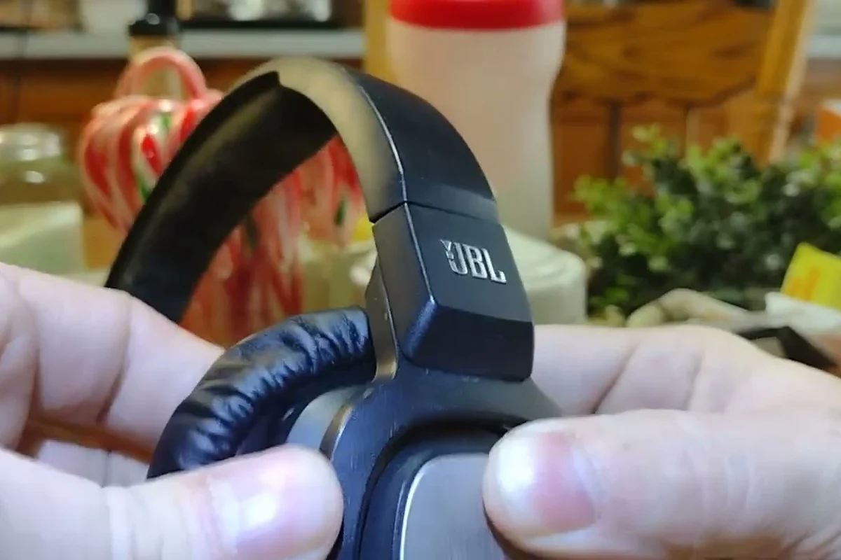 Hands reattaching JBL over-ear headphone pads to an earcup groove