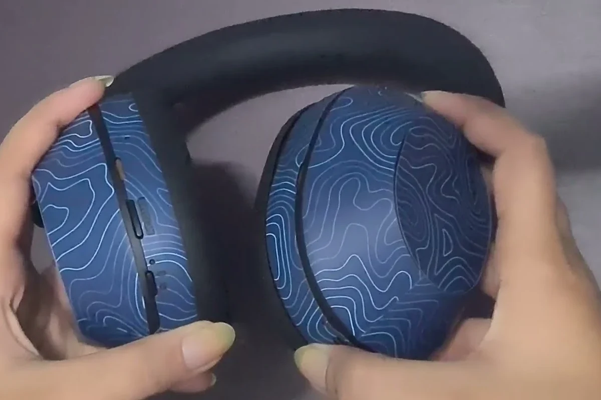 Sony wireless headphones pausing on a desk with a phone and Bluetooth settings nearby