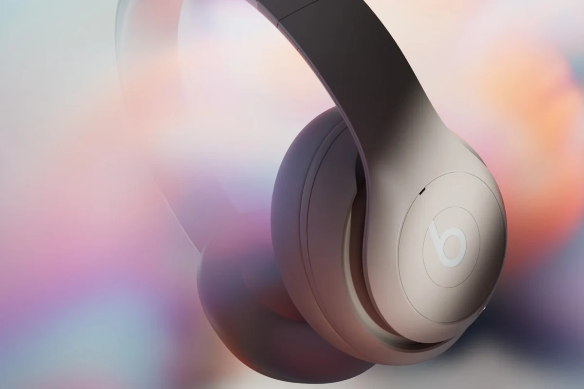 Person turning on Beats headphones with a power button near a charging case on a clean desk