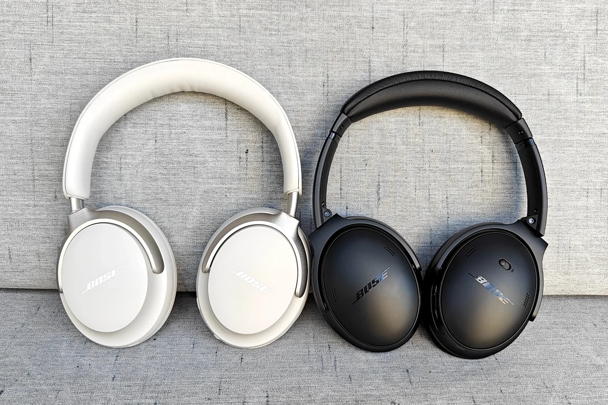 Bose QC Ultra headphones on a desk with phone, laptop, and travel case