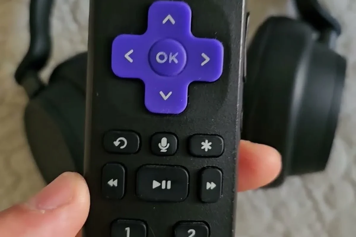 Person using headphones with a Roku TV for private listening in a living room