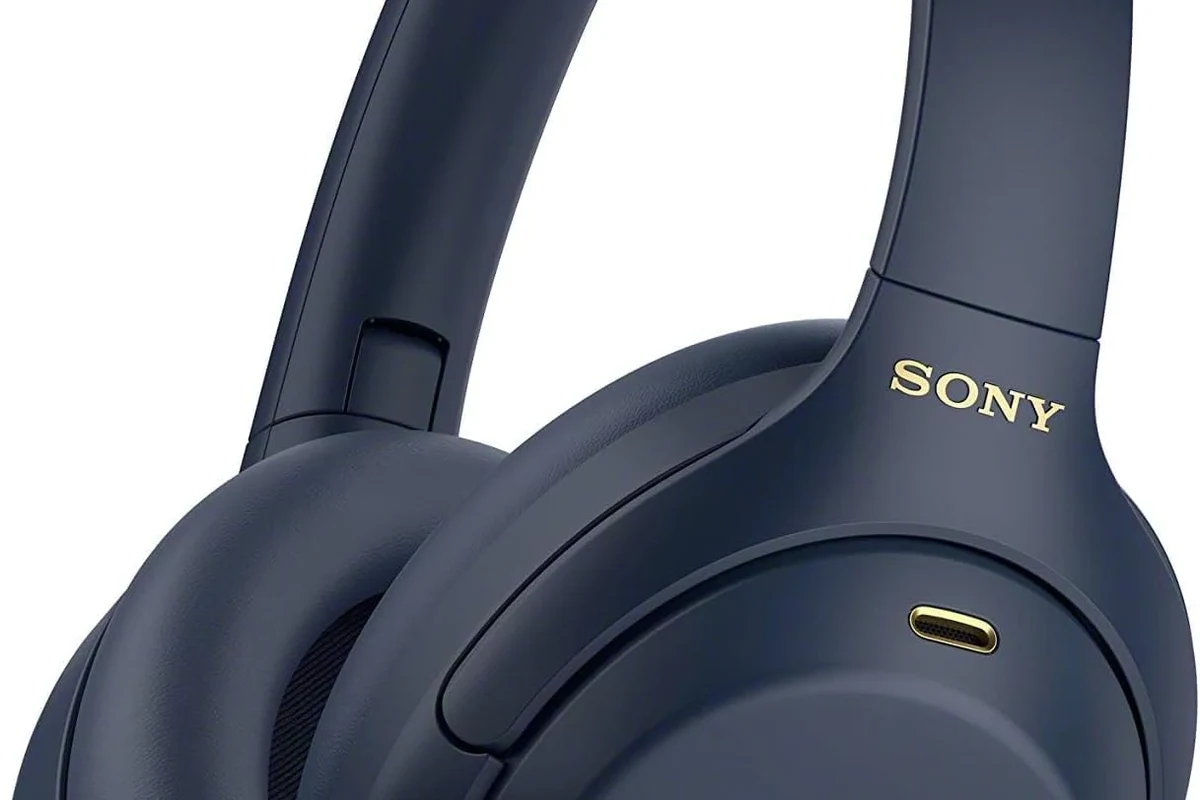 Sony WH-1000XM4 over-ear wireless headphones on a desk with phone and charging cable