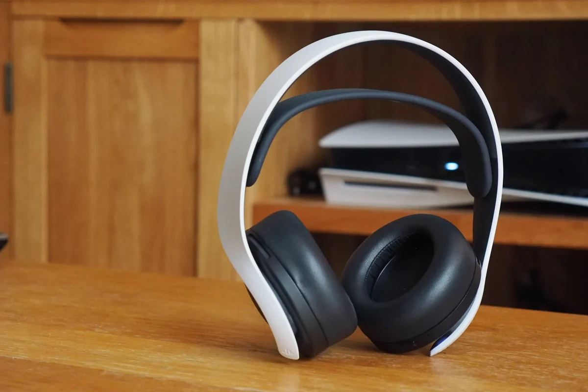 Wireless gaming headphones connected to a PS5 console beside a DualSense controller
